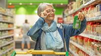 Portrait smiling senior woman making purchases in the supermarket selecting checking a product. Caucasian elderly customer in gr