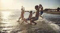 Senior man running and jumping to the sea with grandchildren