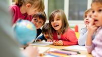 Preschool teacher and children using globe.