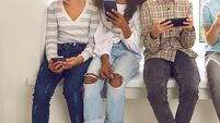 Children sitting on windowsill and ignoring real life immersed in their cell phones