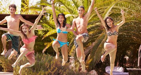 Group Of Teenage Friends Jumping Into Swimming Pool
