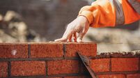 Bricklayer laying another brick in the wall on construction site for sturdy wall