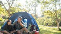 Father and son holding a fishing rod outside the tent