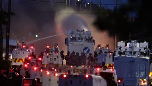 <p>Police fire a water cannon towards rioters after they set fire to wheelie bins and removed a garden fence to use as a shield against the water cannon on Antrim Road, at the Sandyknowes roundabout in Newtownabbey. Picture: PA/PA Wire</p>