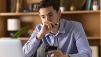 Young businessman concentrating while holding credit card and using laptop for online shopping or banking
