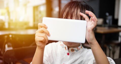 Asian Chinese little girl playing smartphone at outdoor cafe