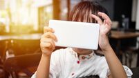 Asian Chinese little girl playing smartphone at outdoor cafe