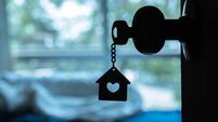 House key with home keyring in keyhole on wood door, copy space