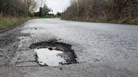 Deep road pothole filled with rainwater.