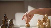 Child's hand holding chess figure while playing chess. Little clever child playing chess at home. Education concept.