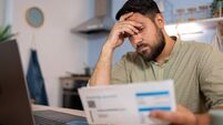 Worried man checking bills and looking at financial analysis of expenses at home.