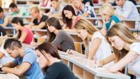 Large group of students writing in notebooks.