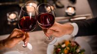 Close up of young couple toasting with glasses of red wine at restaurant