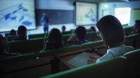 Over the Shoulder Footage of a Female Student Taking Down Notes in a Notebook, Sitting in College Auditorium on a Lecture. Young