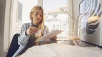 Young Woman Student Reading Paper Financial Statements At Home Office Desk
