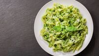 plate of pasta with pesto sauce on dark background