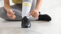 Teenage girl tying shoelace of tap shoe indoors, closeup