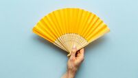Hand holding hand fan made of bamboo and paper