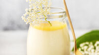 1405556986 Homemade elder flower dessert panna cotta, mousse or pudding in a portion glass jar with lemon curd and fresh flowers.