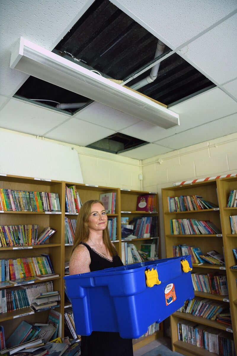 Michelle in the school's library with several plastic containers and towels on the floor where the roof above has a substantial leak, rendering the room unusable for the whole school community. Picture: Moya Nolan Michelle in the school's library with several plastic containers and towels on the floor where the roof above has a substantial leak, rendering the room unusable for the whole school community. Picture: Moya Nolan