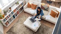 Woman working at home using her laptop and looking at documents