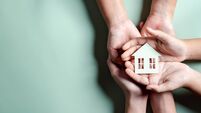iStock-1455289321.jpg Hands holding wooden house, family home, homeless housing, mortgage crisis and home protecting insurance, international day of f