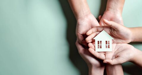 Hands holding wooden house, family home, homeless housing, mortgage crisis and home protecting insurance, international day of f
