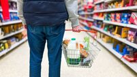 Man holding shopping basket with bread and milk groceries in supermarket