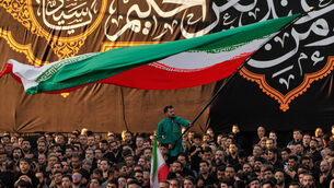 A man waves an Iranian flag as people beat their chests during a mourning ceremony in Tehran, Iran (Vahid Salemi/AP) A man waves an Iranian flag as people beat their chests during a mourning ceremony in Tehran, Iran (Vahid Salemi/AP)