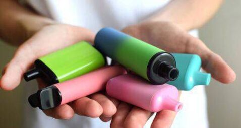 Many colorful electronic cigarettes in the hands of a teenager. Vaping with nicotine. Danger for teenagers.