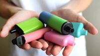 Many colorful electronic cigarettes in the hands of a teenager. Vaping with nicotine. Danger for teenagers.