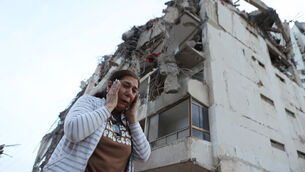 A woman walks past a building damaged during an earthquake in La Guaira (Pedro Mattey/AP)