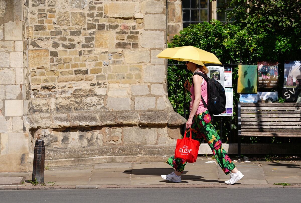 A person using an umbrella to shield from the sun in Cambridge in the UK. A person using an umbrella to shield from the sun in Cambridge in the UK.