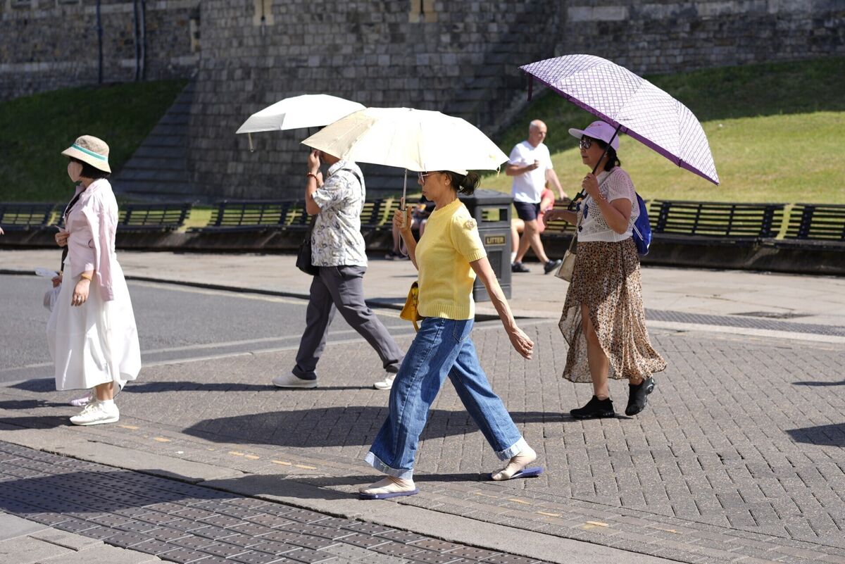 People use umbrellas to shade themselves from the sun. Photo: Andrew Matthews/PA Wire People use umbrellas to shade themselves from the sun. Photo: Andrew Matthews/PA Wire