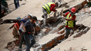 Rescue worker search through the rubble of a collapsed building (Pedro Mattey/AP)