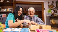 Senior man with Alzheimer's disease having fun  with female doctor while playing with wooden toys