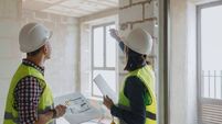 two engineers, a man and a woman in white helmets and green protective vests