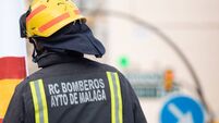Fire workers hoisting a flag of Spain and a gratitude message to health workers