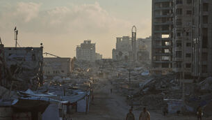<p>Palestinians walk along a street surrounded by buildings destroyed in Israeli military strikes during the Israel-Hamas war, in Gaza City (Jehad Alshrafi/AP)</p>