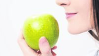 Young beautiful brunette girl on a white background holding a fresh green apple.