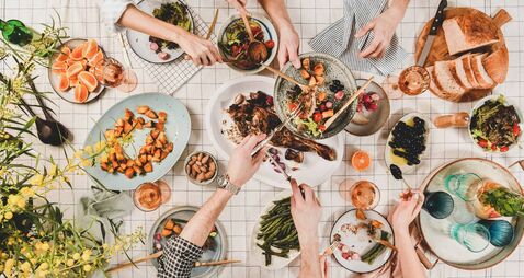 Peoples hands with various snacks and blooming mimosa, top view
