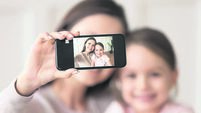 Happy mother holding phone taking selfie on cellphone with daughter