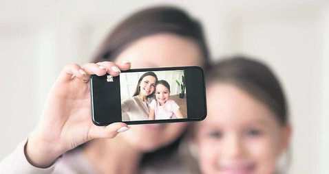 Happy mother holding phone taking selfie on cellphone with daughter
