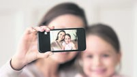 Happy mother holding phone taking selfie on cellphone with daughter