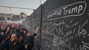 Mourners write messages on a wall, including one in English that reads ‘We will kill Trump’, during the funeral ceremonies for late Iranian supreme leader Ayatollah Ali Khamenei in Tehran, Iran (Altaf Qadri/AP)