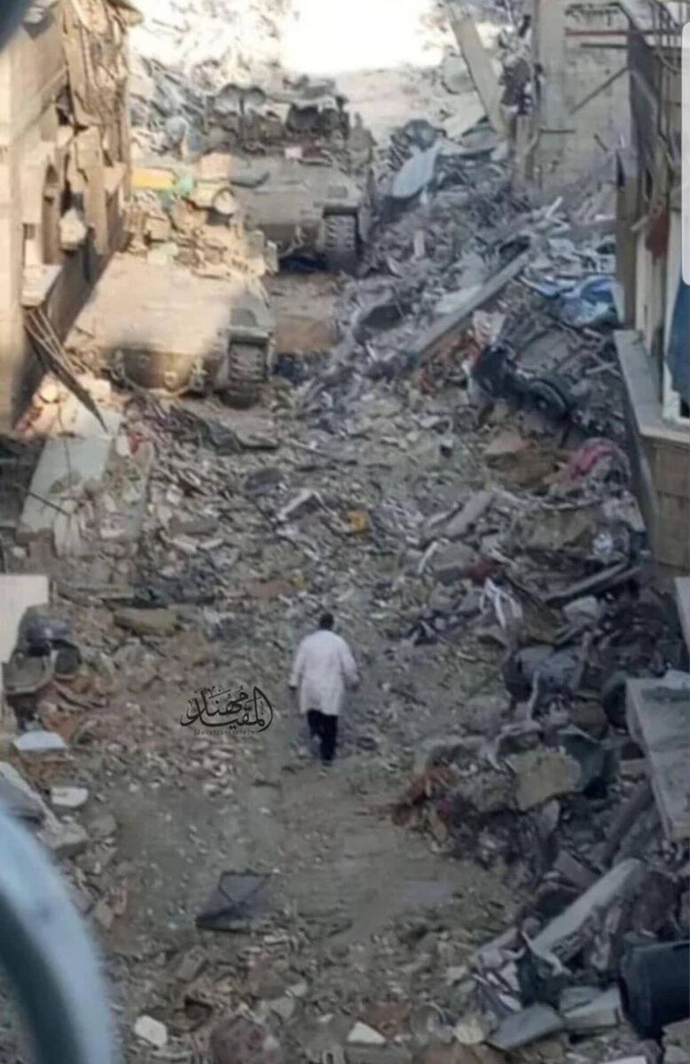 An image of Dr. Hussam Abu Safiya, director of Kamal Adwan Hospital taken before his arrest at Kamal Adwan Hospital, walking towards the Israeli Army tanks in his lab coat. 