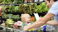 Father with daughter (9-12 months) and shopping list in supermarket