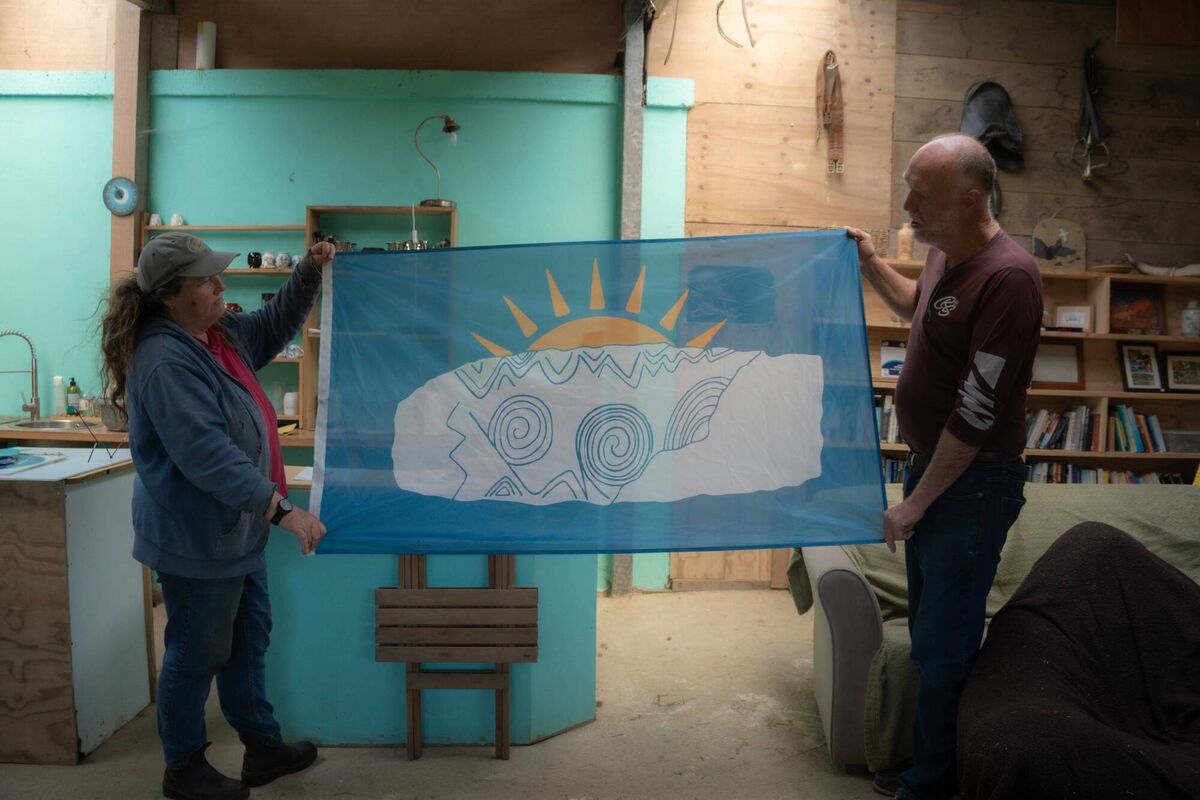 Fiona MacLachlan and Séamus Ó Drisceoil unfurl a flag featuring a neolithic inspited design