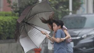 People struggle with an umbrella in a rain caused by Typhoon Bavi in Taichung, Taiwan (Chiang Ying-ying/AP) People struggle with an umbrella in a rain caused by Typhoon Bavi in Taichung, Taiwan (Chiang Ying-ying/AP)
