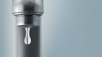 Sink faucet dripping with the water drop in focus